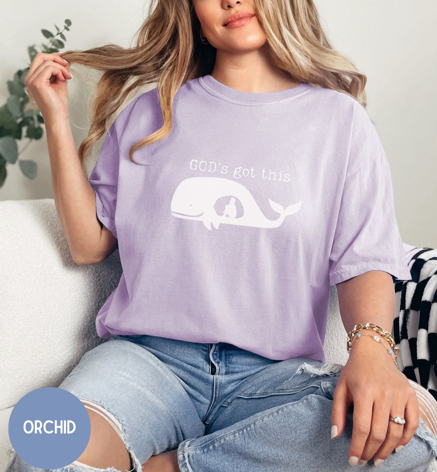 a woman sitting on a couch wearing a purple shirt that says god's not