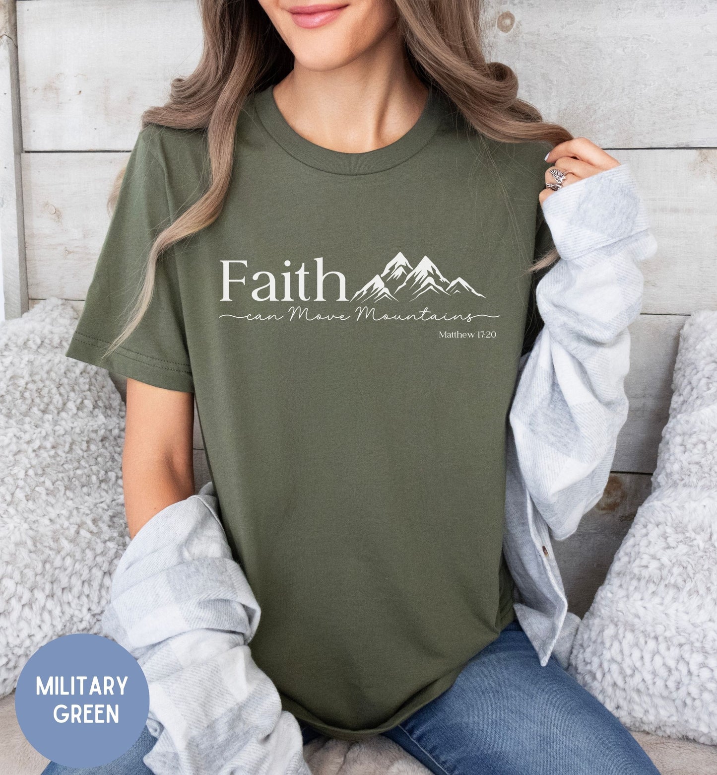 a woman sitting on a bed wearing a green faith t - shirt