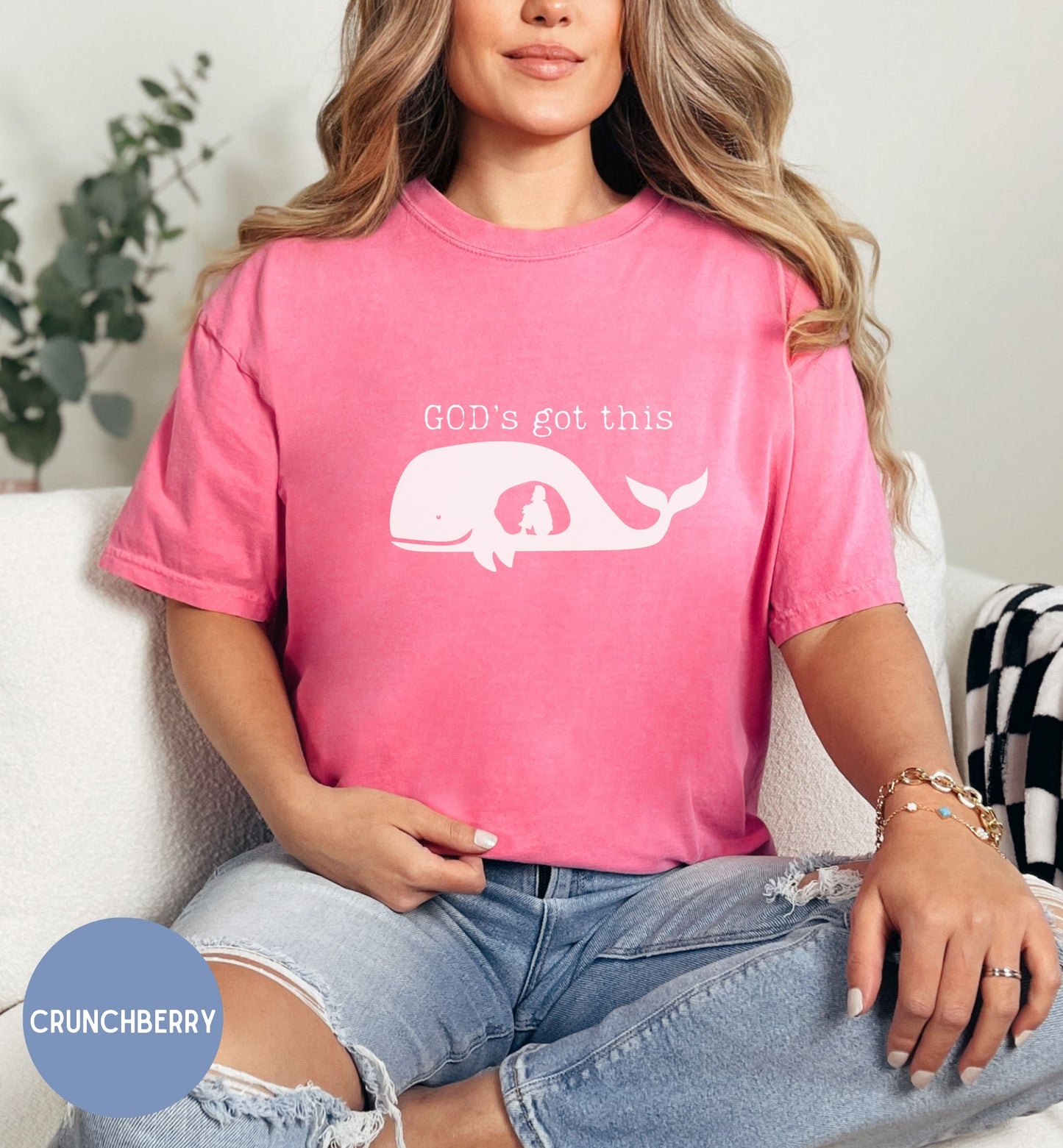 a woman sitting on a couch wearing a pink shirt