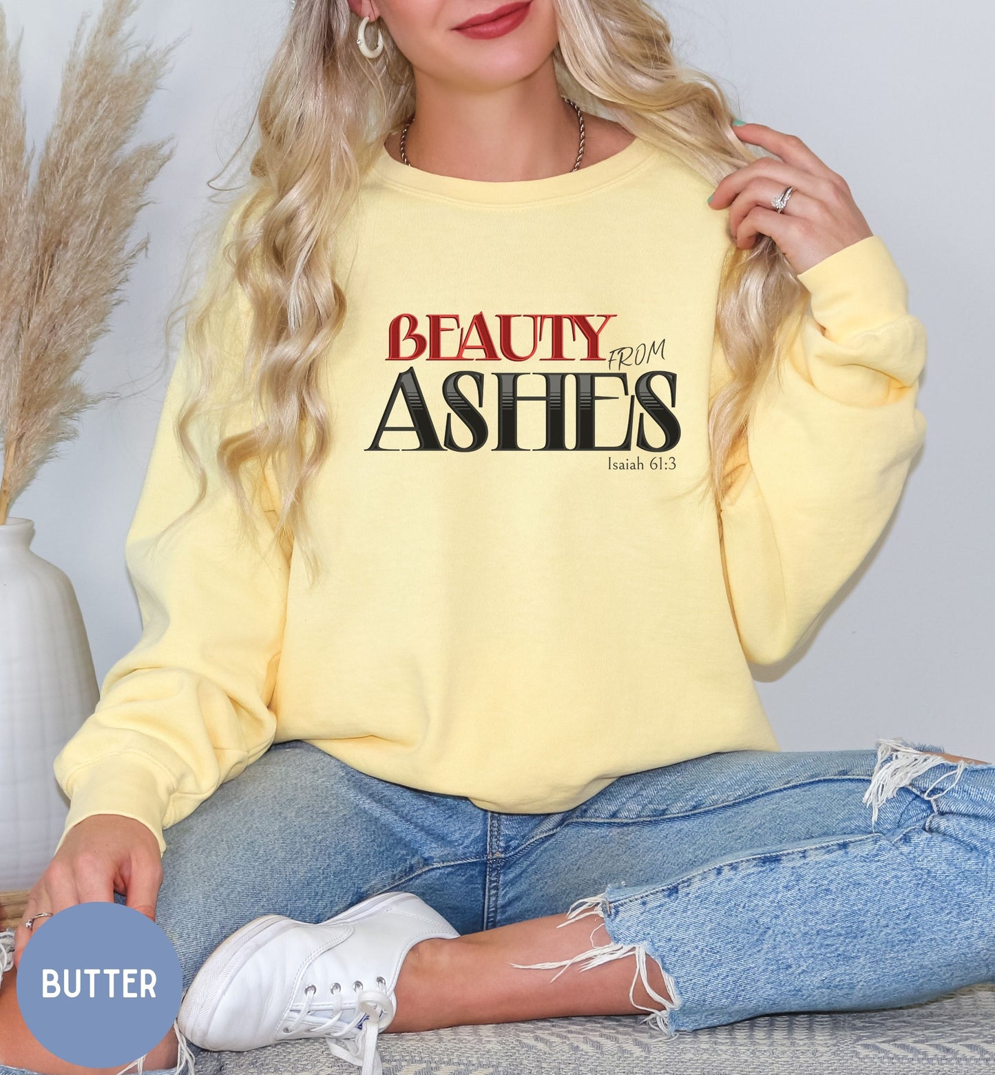 a woman sitting on a bed wearing a yellow sweatshirt