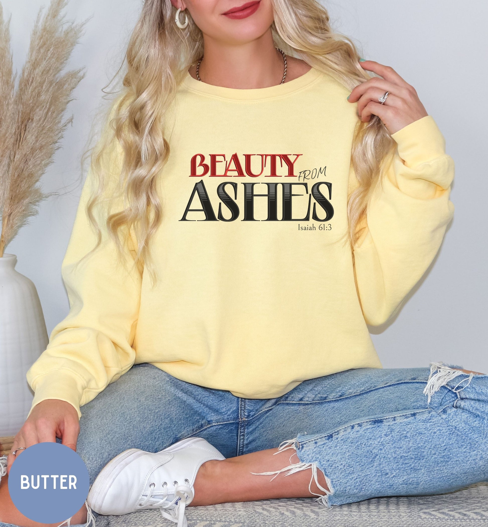 a woman sitting on a bed wearing a yellow sweatshirt